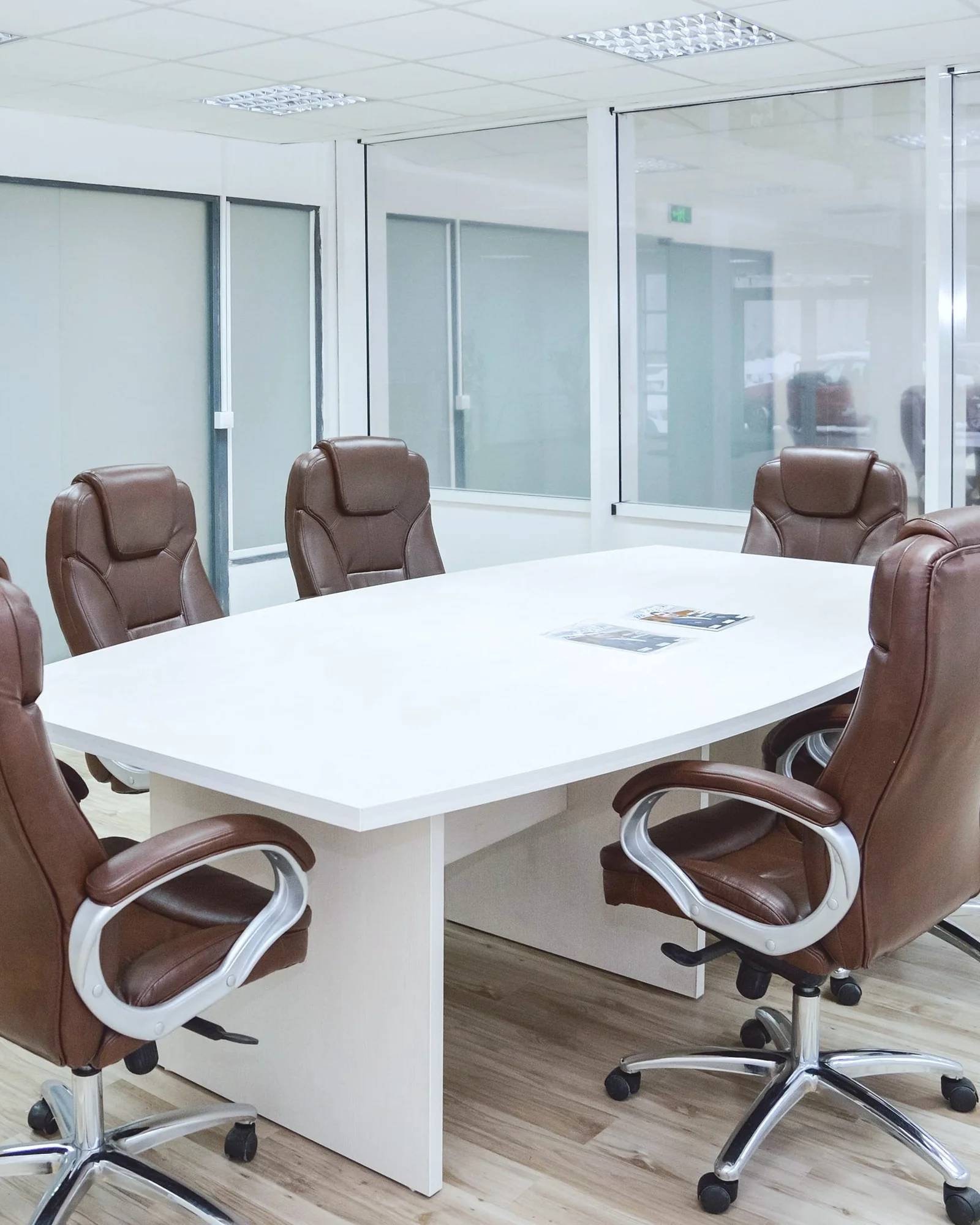 IMG P08 group Salle de réunion avec table blanche, fauteuils en cuir marron et parois vitrées.