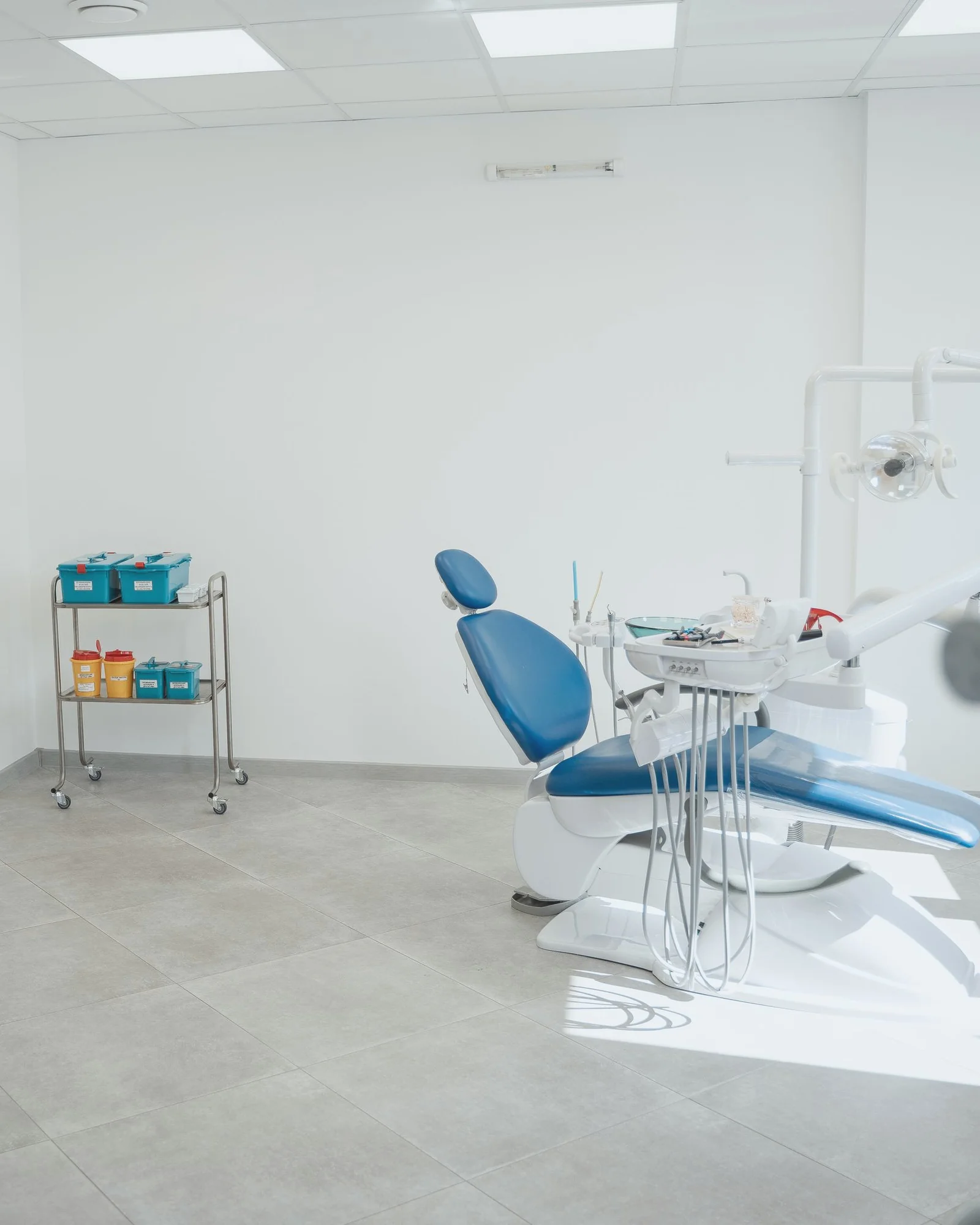 IMG S10 studi Studio dentistico con poltrona blu, riunito e carrello con contenitori.